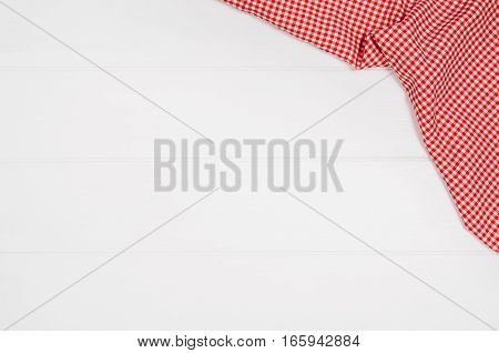 Top view of red checkered napkin or tablecloth on white wooden table with visible planks, texture and copy space for text.