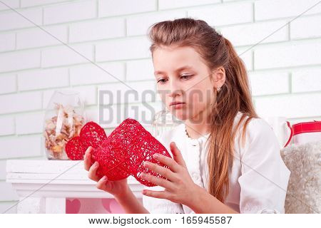 Upset young girl looking on heart in her hands