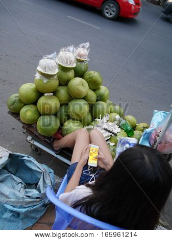 03 january 2017 Long Nget Street 250 phnom penh cambodia young fruit sales woman playing game on smartphone editorial image