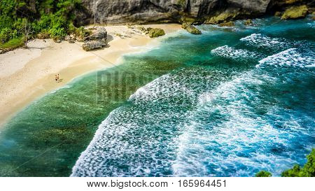 Couple on beautiful Atuh Beach with White Long Waves, Nusa Penida, Bali, Indonesia.