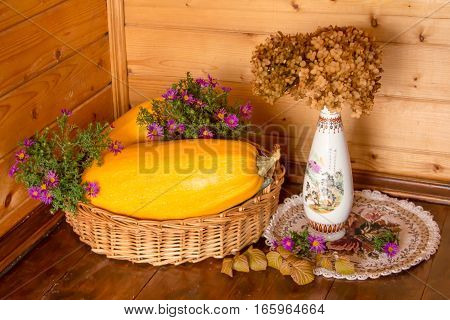 Still life of zucchini, vases, flowers and baskets.