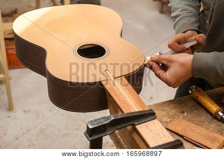 The worker glues guitar in the studio for the production of guitars.