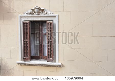 Ornamented Window with Wooden Shutters on Yellow Wall