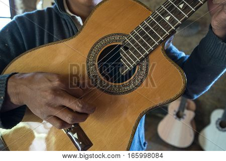 July 22, 2016 San Bartolome, Ecuador: a luthier holds up a finished guitar in his small rural shop