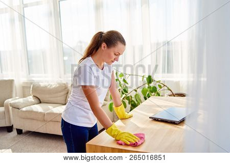 Woman In White Shirt And Yellow Protective Rubber Gloves Cleaning At Home And Wiping Dust On Wooden 