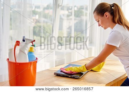Woman In White Shirt And Yellow Protective Rubber Gloves Cleaning At Home And Wiping Dust With Pink 
