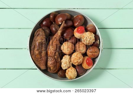 high angle view of some chestnuts, some panellets and some roasted sweet potatoes, as a typical snack eaten in All Saints Day in Catalonia, Spain, called castanada