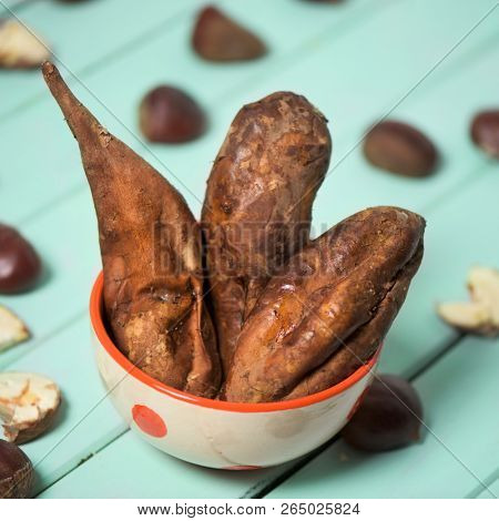 closeup of a bowl with roasted sweet potatoes on a pale green wooden table, next to some chestnuts