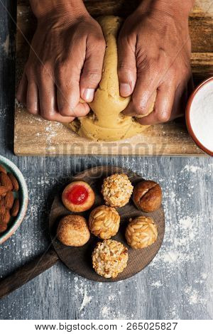 high angle view of a young caucasian man preparing some panellets, sweet food typically eaten in All Saints Day in Catalonia, Spain