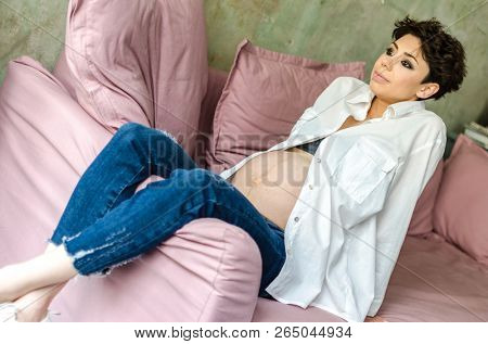 Beautiful pregnant woman sitting on sofa at home