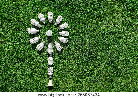 Energy Saving Light Bulbs On Grass Forming Flower. Green Energy Concept