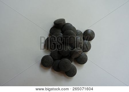 Handful Of Round Black Pills Of Chelated Iron From Above