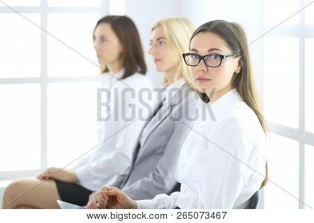 Attractive Businesswoman At Meeting Or Conference Against The Background Of Colleagues. Group Of Bus