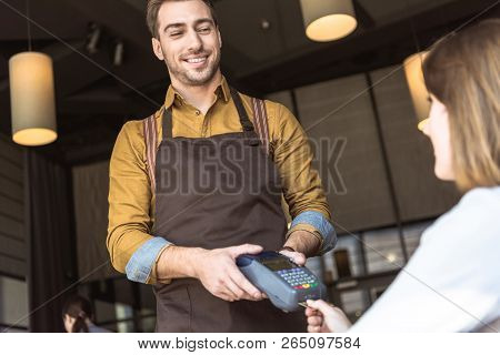 Happy Young Waiter Holding Payment Terminal While Client Inserting Credit Card