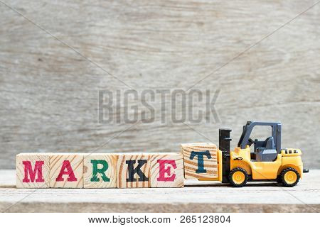 Toy Forklift Hold Letter Block T To Complete Word Marekt On Wood Background