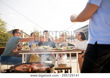 leisure and people concept - happy friends toasting drinks at barbecue party on rooftop in summer