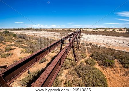 Australia â Old Ghan railway bridge over a dried-out river bed at the outback desert under blue sky 