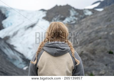 Back View Of A Blonde Woman With Pigtail Braids Looking At The Worthington Glacier In Valdez Alaska,