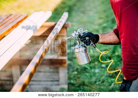 Industrial Carpenter Painting Timber With Spraygun, Outdoors