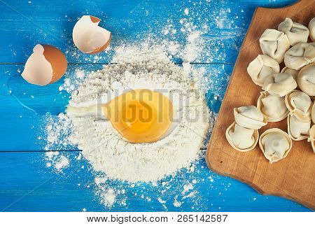 Uncooked Russian Pelmeni On Cutting Board And Ingredients For Homemade Pelmeni With Fresh Egg On Blu