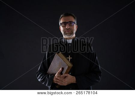Priest portrait with Holy Bible in hands isolated