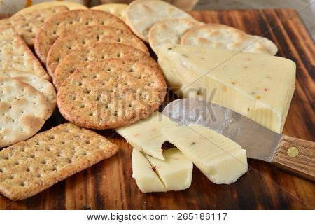 Pepperjack Cheese With A Cheese Knife And Gourmet Crackers On A Cutting Board