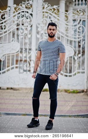 Handsome Tall Arabian Beard Man Model At Stripped Shirt Posed Outdoor Against Royal Iron Gates. Fash