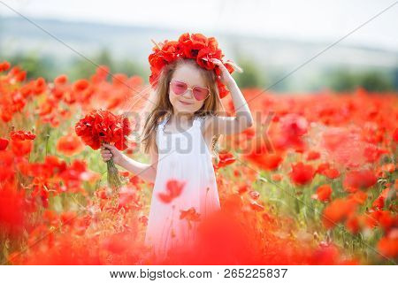 A Small Pre-school Girl With Long Curly Hair, Dressed In A White Sleeveless Dress, Wears Pink Glasse