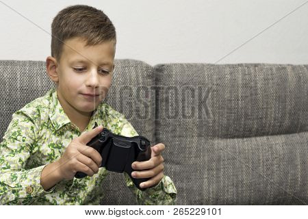 Boy Playing Video Games With Joystic Sitting On Sofa