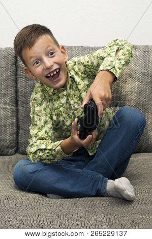 Boy Playing Video Games With Joystic Sitting On Sofa