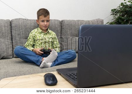 Boy Playing Video Games With Joystic Sitting On Sofa