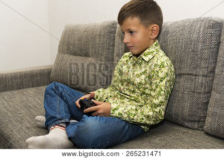 Boy Playing Video Games With Joystic Sitting On Sofa