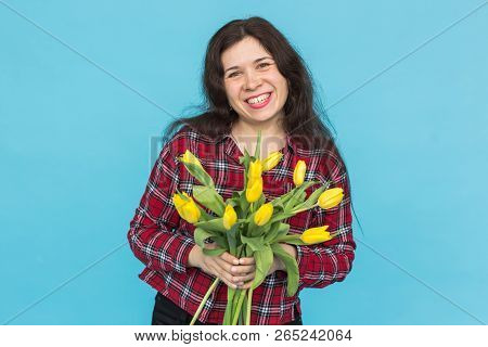 Laughing Young Caucasian Woman With Bouquet Of Tulips On Blue Background.