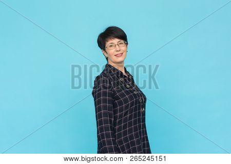 Middle Aged Woman With Pixie Haircut On Blue Background With Copy Space