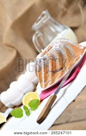Homemade Bundt Cake Sprinkled With Sugar, Lemon, Melissa, Milk, Eggs And Butter, Vertical Photo
