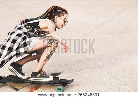 Young Girl With Tattoo Rides On A Longboard