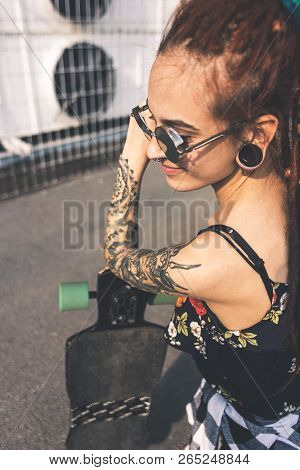 Young Girl With Tattoo And Dreadlocks On Urban Industrial Background