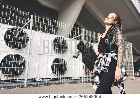 Young Girl With Tattoo And Dreadlocks On Urban Industrial Background