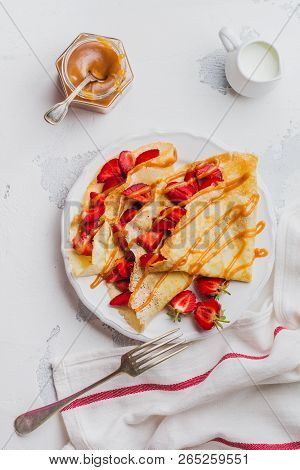 Сrepes With Fresh Strawberries And Caramel On Light Concrete Old Table Background. Top View.