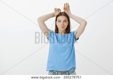 Cute Like Little Bunny. Playful Charming Adult Woman In Blue T-shirt, Holding Hands On Head And Mimi
