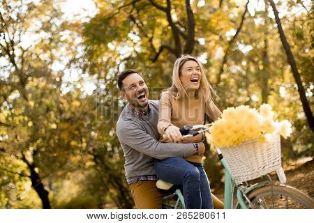Active Young Couple Enjoying Riding Bicycle In Golden Autumn Park
