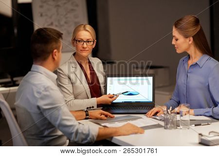 business, deadline and technology concept - coworkers working with charts on laptop computer screen late at night office
