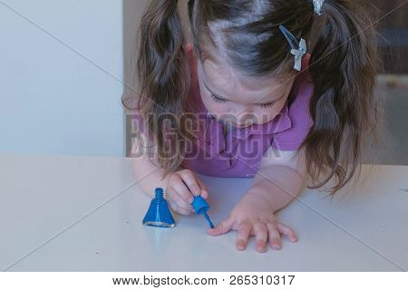 Little Cute Girl Paints Her Nails With Blue Varnish.