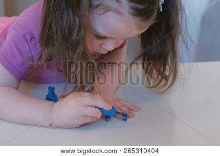 Little Cute Girl Paints Her Nails With Blue Varnish.