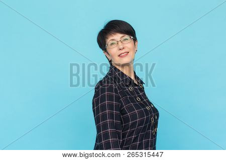 Middle Aged Woman With Pixie Haircut On Blue Background With Copy Space