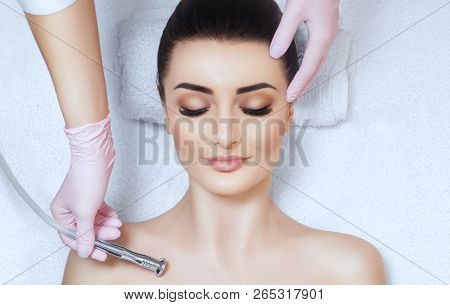 The Cosmetologist Makes The Procedure Microdermabrasion On The Collarbone And Neck Of A Beautiful, Y