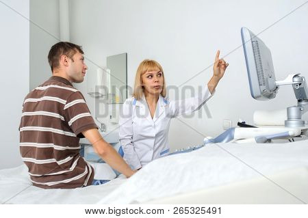 The Lady Ultrasunography Doctor Is Explaining To The Patientat Divice, In Medical Office