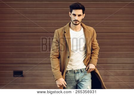 Young Man Wearing Winter Clothes In The Street. Young Bearded Guy With Modern Hairstyle With Coat, B