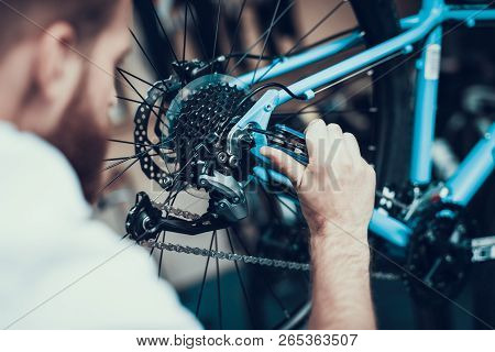 Bike Mechanic Repairs Bicycle In Workshop. Closeup Portrait Of Young Blurred Man Examines And Fixes 
