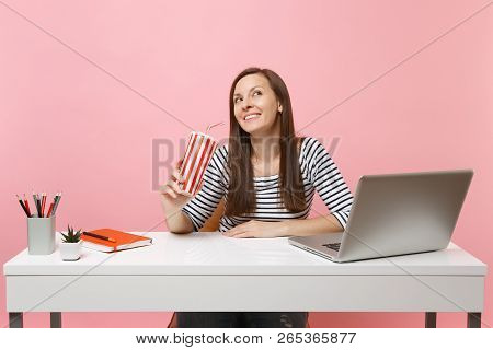Smiling Woman Looking Up Dreaming Holding Plactic Cup With Cola Or Soda Sit, Work At White Desk With